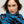 Gros plan sur un foulard en fine laine mérinos bleu vif à motif végétal aux formes organiques noires et tiges rouges, bordure rayée rose, enroulé autour du cou, Princesse & Dragon