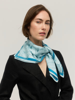Foulard carré en soie et coton bleu ciel à motif floral dessiné au trait, bordure bleu vif, noué au cou, Princesse & Dragon