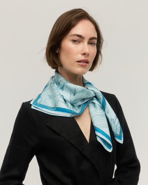 Foulard carré en soie et coton bleu ciel à motif floral dessiné au trait, bordure bleu vif, noué au cou, Princesse & Dragon