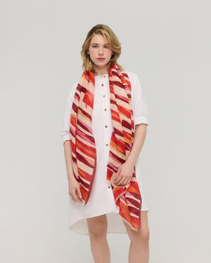 Foulard graphique rouge et orange en lin et coton porté autour du cou, Princesse & Dragon Montréal