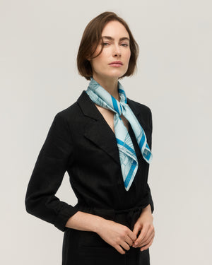 Light blue silk and cotton square scarf with line-drawn floral pattern and bright blue border, tied at the neck, Princesse & Dragon
