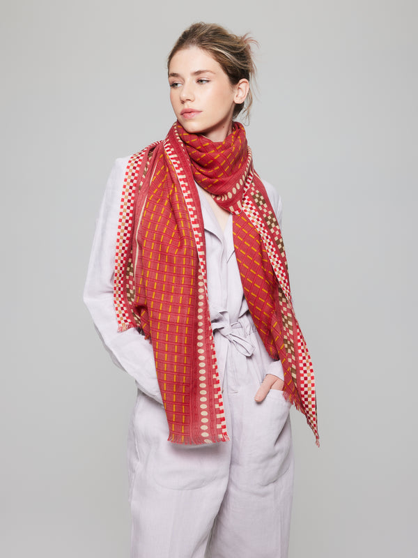 Foulard en laine mérinos doux et léger, dans des tons de rouge et jaune avec des accents de rose. Fait à la main, idéal pour les saisons fraîches et froides.